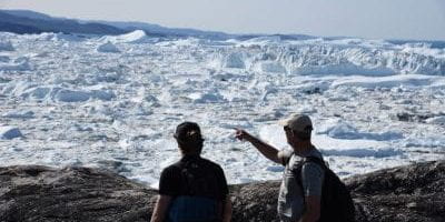 Mark Carey and Casey Shoop standing in front of and facing an icy landscape, with Carey pointing.